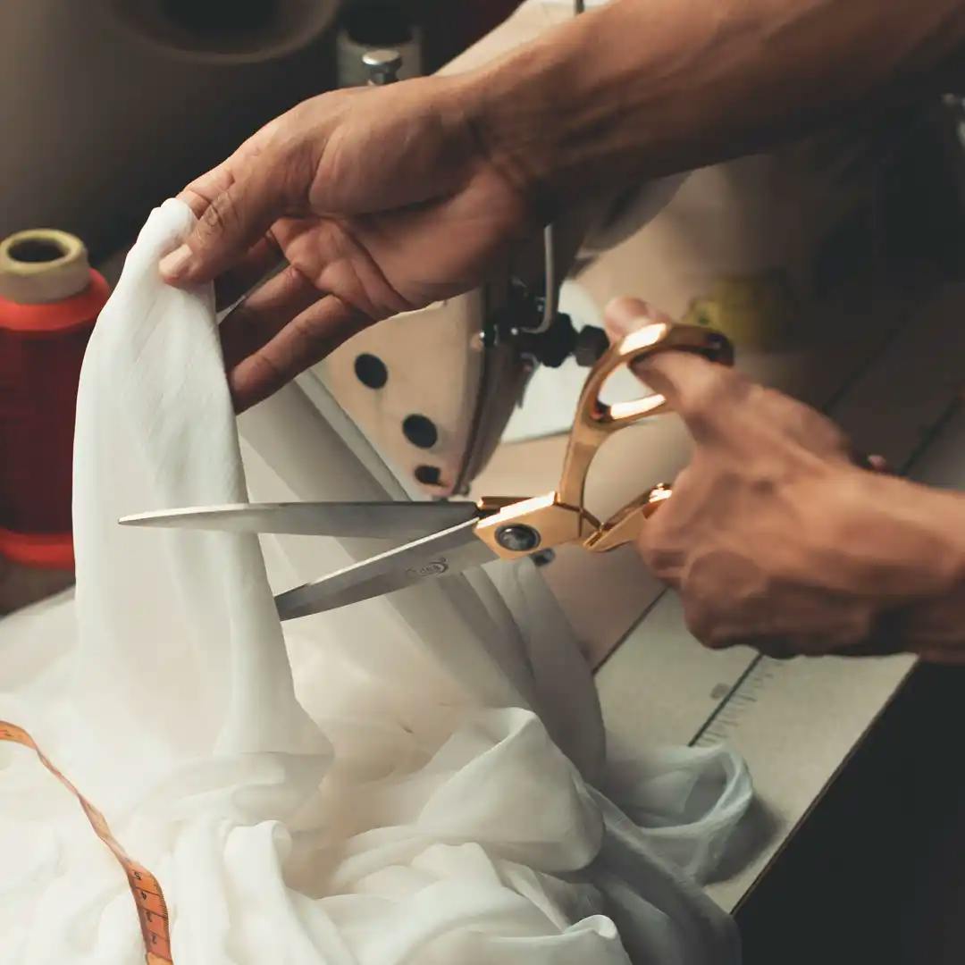 A photo of a man cutting a piece of cloth with a pair of scissors